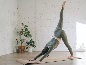 a person wearing grey active wear doing yoga on a mat